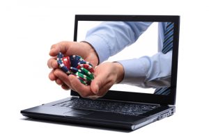 DGOJ: Informe anual de mercado de juego online estatal de 2018. Fotografía de unas manos con fichas de casino saliendo de un ordenador portatil