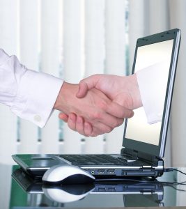 Contratos de juego online. Orientaciones de la DGOJ. Por qué y Para qué. Fotografía de dos manos estrechandose una sale de un ordenador portatil